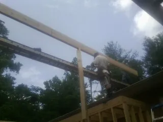 Carpenter setting a ridge beam over a new addition frame — Ice Dam Removal by Roofing Brothers in Yorba Linda