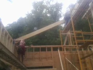 Carpenter raising a rafter beam on a new second story frame in Yorba Linda