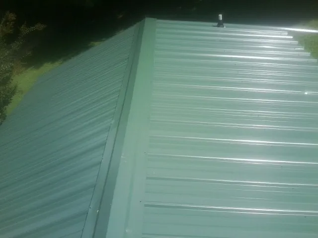 New green metal panels meeting at the ridge of a roof — Flat Roof Repair work by our crew in Yorba Linda