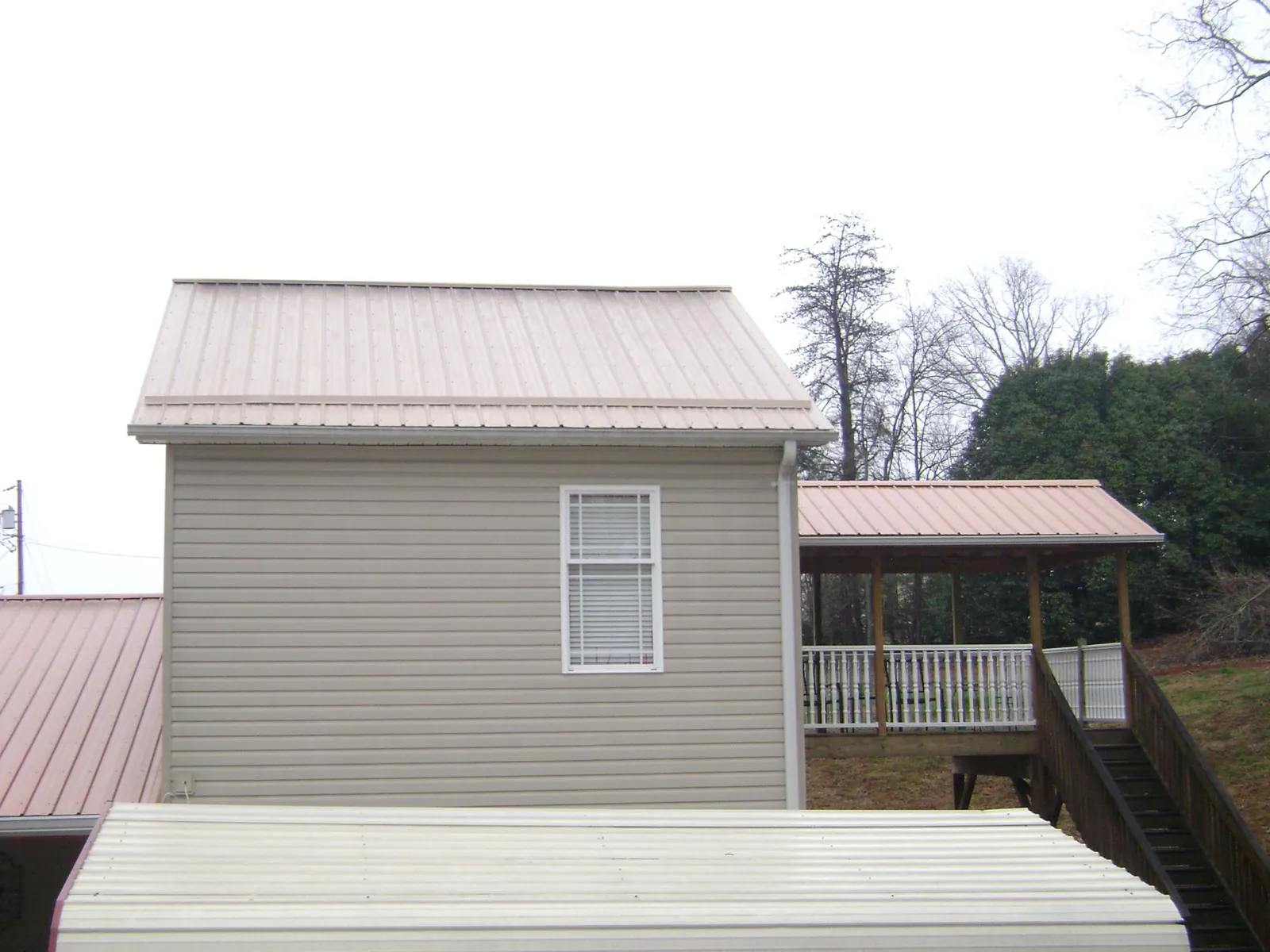 Tan metal roofs on a two story addition and attached porch, from a Roof Replacement job in Yorba Linda