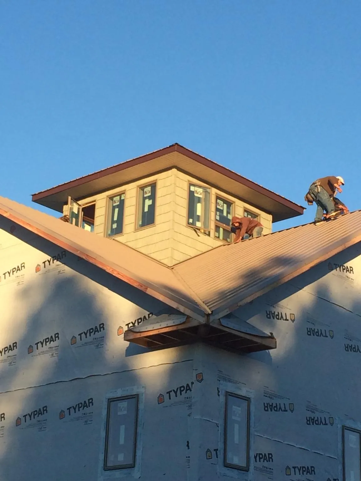 Roofers working around a rooftop cupola on a new metal roof at sunset — Roof Waterproofing in Yorba Linda by Roofing Brothers